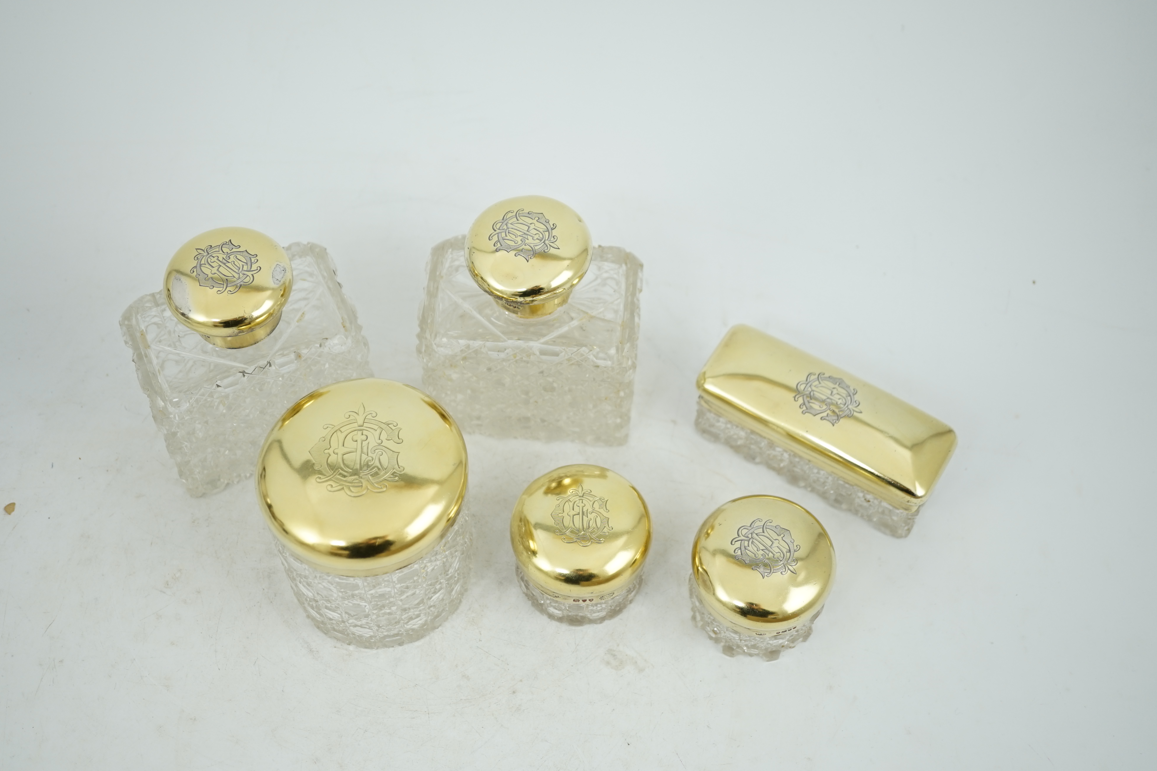 A matched suite of six late Victorian silver gilt mounted cut glass toilet jars two by Charles & George Asprey, London, 1893, tallest 12.2cm.